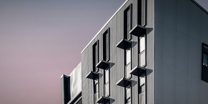 A contemporary commercial building with a ribbed metal and concrete facade at dusk