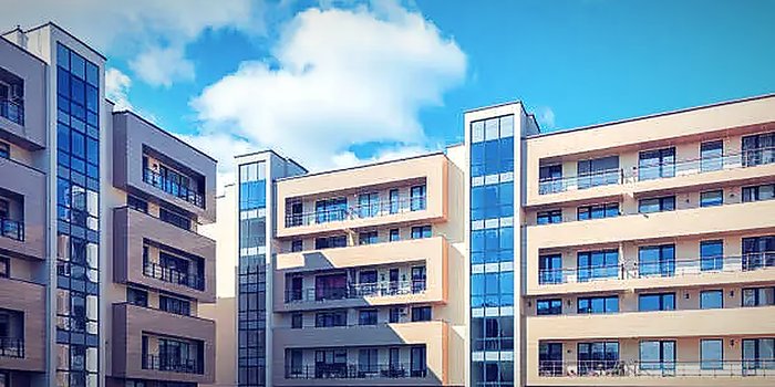 A premium apartment complex with landscaped grounds under a blue sky