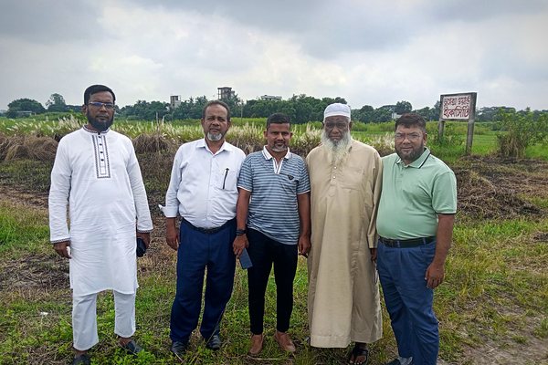 Silver Moon team standing at the site boundary, with a ward marker board in the field behind them
